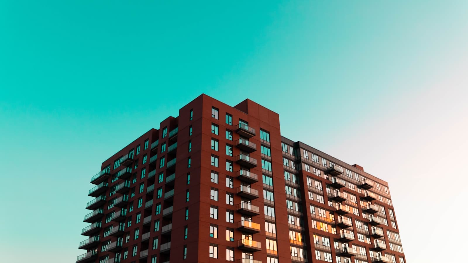 The upper floors of a brick apartment block against the sky at dusk